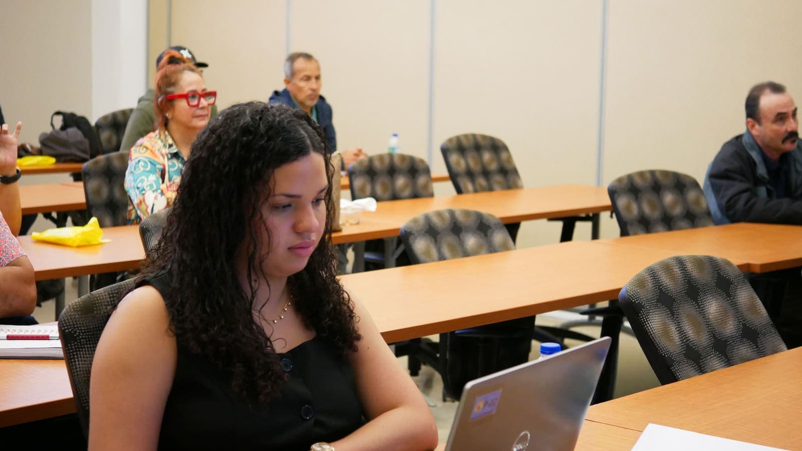 Servidores públicos asisten a un taller de IA en 2026, una de ellas trabaja con su laptop en primer plano.